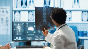 Doctor analyzing an X-ray while reviewing medical scans on a computer