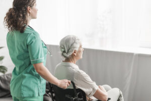 Healthcare worker supporting elderly patient in wheelchair for healthcare tele-operations