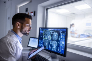 Radiologist reviewing digital brain scans on a computer during an MRI procedure in a modern medical facility