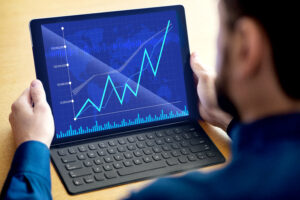 Person holding tablet with rising financial graph on screen.
